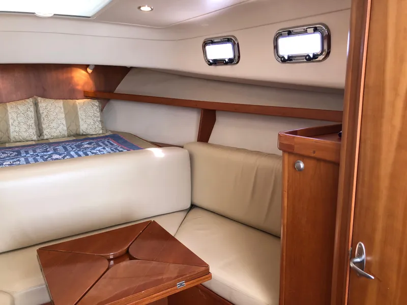 Slide: The Image of 2003 Mainship 30 Pilot II cabin interior with beige seating and wooden accents. - 27