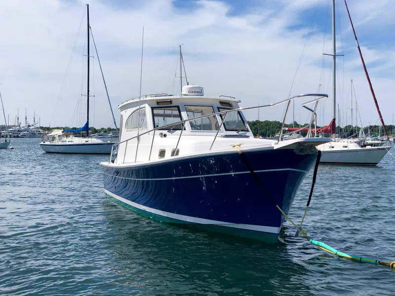 Slide: The Image of 2003 Mainship 30 Pilot II Hardtop boat docked in a marina, surrounded by sailboats. - 3