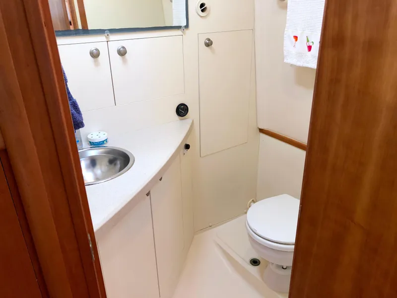 Slide: The Image of 2003 Mainship 30 Pilot II boat bathroom with sink, toilet, and storage cabinets. - 31