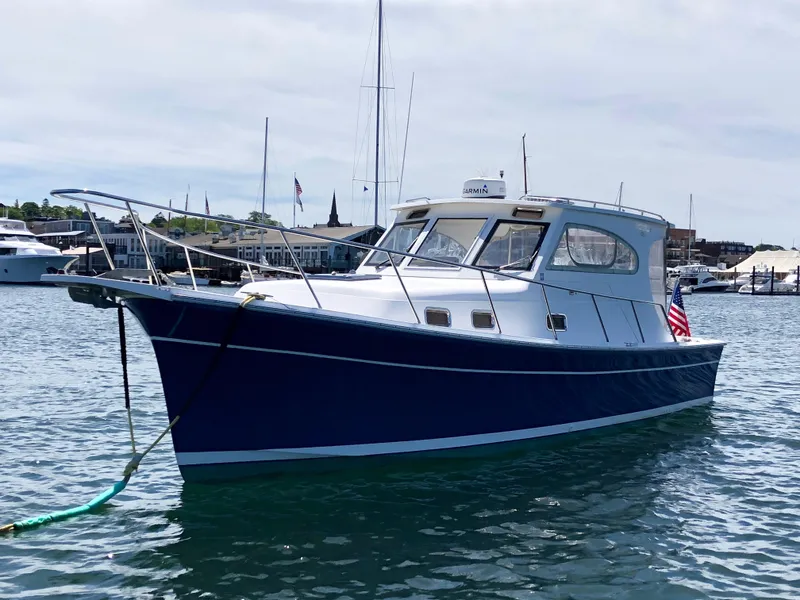 Slide: The Image of 2003 Mainship 30 Pilot II Hardtop boat on water, blue hull, marina background. - 4