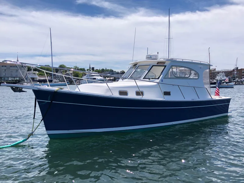 Slide: The Image of 2003 Mainship 30 Pilot II Hardtop boat on water, blue hull, marina background. - 5