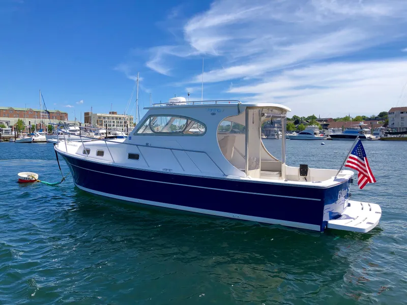 Slide: The Image of 2003 Mainship 30 Pilot II Hardtop boat docked in sunny marina with American flag. - 6