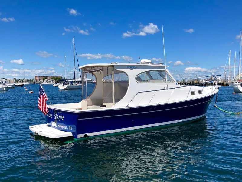 Slide: The Image of 2003 Mainship 30 Pilot II Hardtop boat on water, clear sky, American flag displayed. - 9