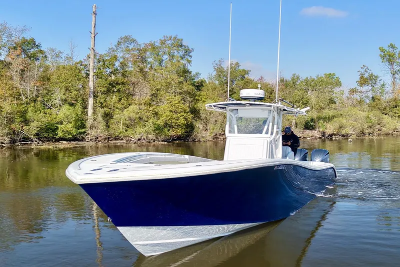 Slide: The Image of 2006 Yellowfin 36 Offshore boat cruising on a calm river with lush greenery. - 11