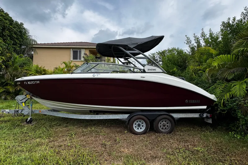 Slide: The Image of 2022 Yamaha Boats 252SE on trailer, parked in a lush garden setting. - 1