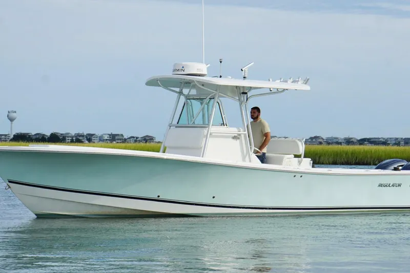 Slide: The Image of 2006 Regulator 32 Forward Seating boat on calm water, with a person at the helm. - 10