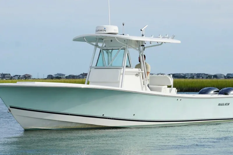 Slide: The Image of 2006 Regulator 32 Forward Seating boat on calm water, coastal background. - 7