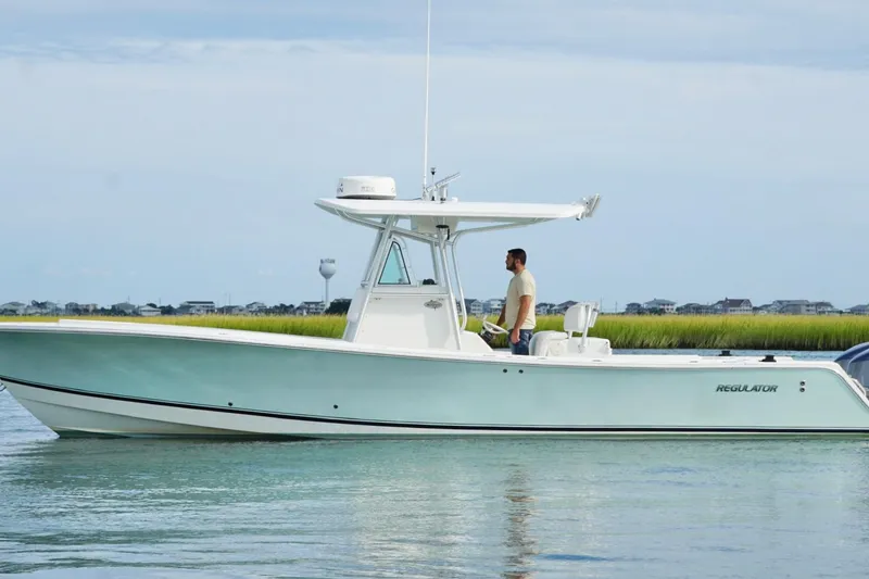 Slide: The Image of 2006 Regulator 32 Forward Seating boat on calm water, with a person standing at the helm. - 8