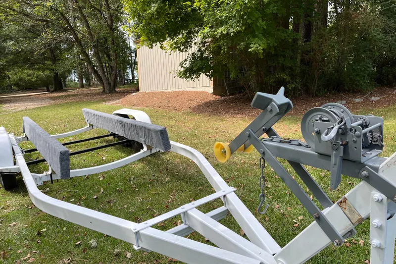 Slide: The Image of Boat trailer on grass, featuring winch and padded supports, surrounded by trees. Century 2102, 2007 model. - 14