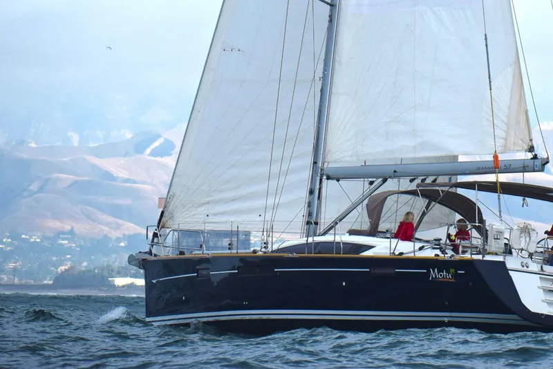 Slide: The Image of Sailing yacht Jeanneau 57, 2013 model, cruising on open water with mountains in the background. - 0