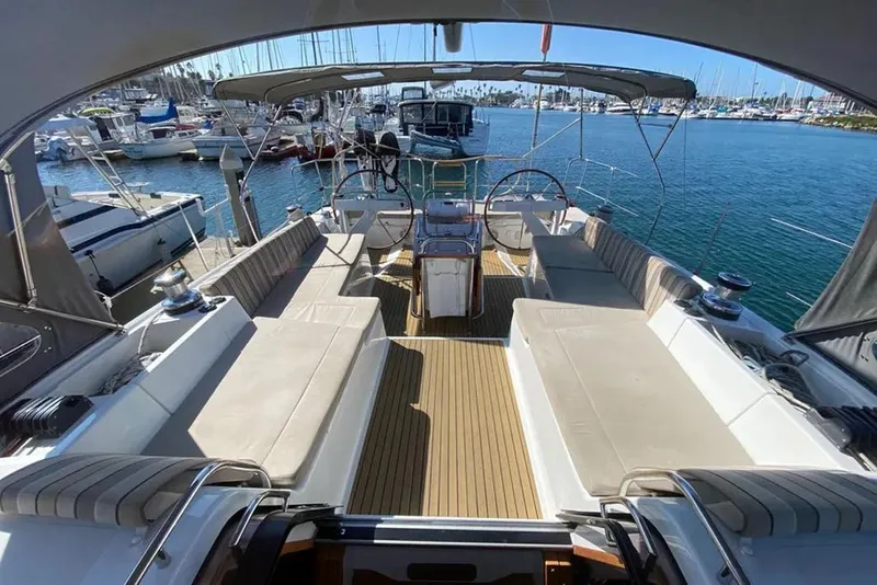 Slide: The Image of 2013 Jeanneau 57 yacht helm with wooden deck, docked in marina under clear blue sky. - 17
