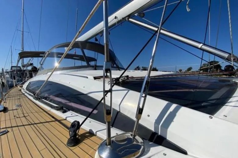 Slide: The Image of 2013 Jeanneau 57 yacht docked in a marina with palm trees and buildings. - 6