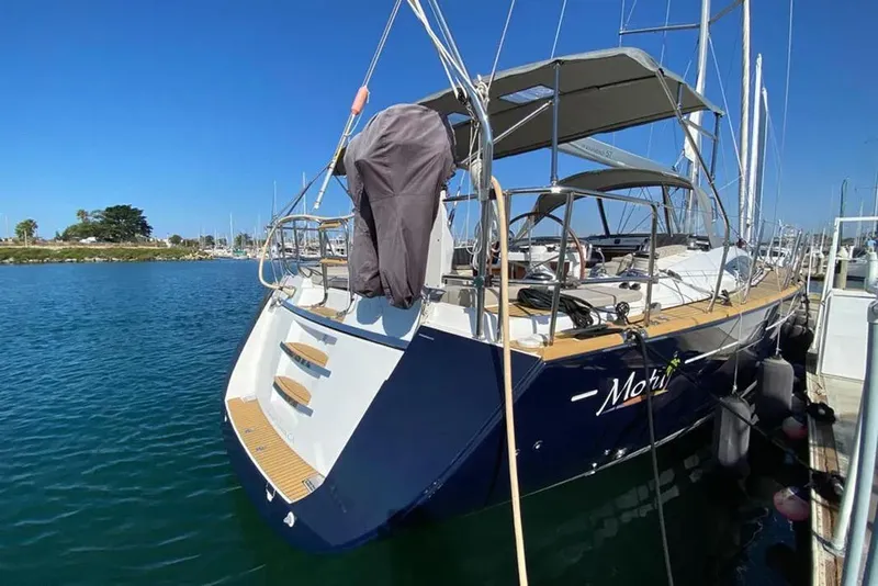 Slide: The Image of 2013 Jeanneau 57 sailboat docked, featuring a sunshade and sleek design. - 9