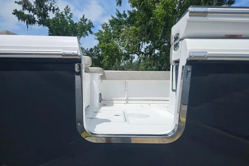 Slide: The Image of 2025 Sea Hunt Gamefish 27 Forward Seating boat interior with open door, trees in background. - 2