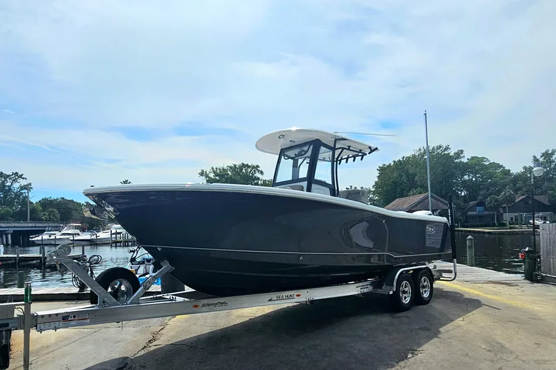 Slide: The Image of 2025 Sea Hunt Gamefish 27 Forward Seating boat on trailer by the water. - 5