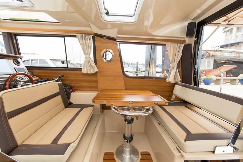 Slide: The Image of Manufacturer Provided Image: Interior of 2021 Ranger Tugs R-27 with beige seating and wooden accents. - 18