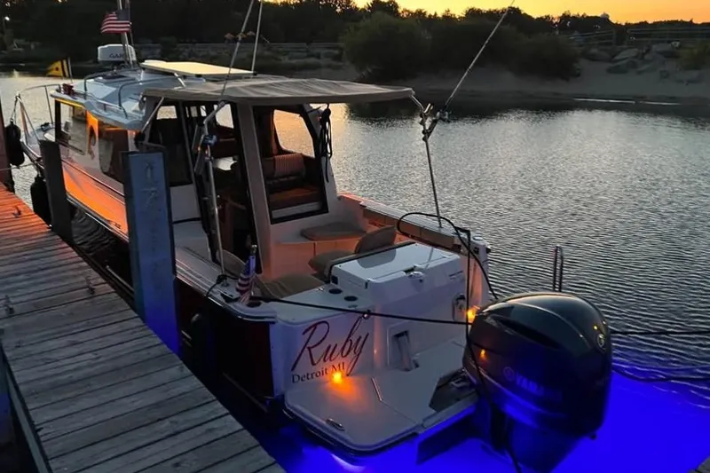 Slide: The Image of 2021 Ranger Tugs R-27 boat docked at sunset with blue underwater lights. - 5
