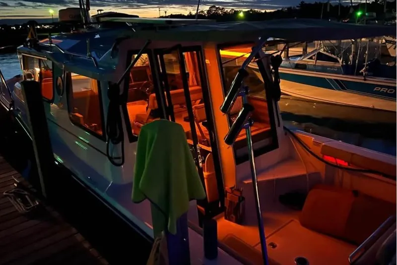 Slide: The Image of 2021 Ranger Tugs R-27 boat docked at sunset with warm interior lighting. - 7