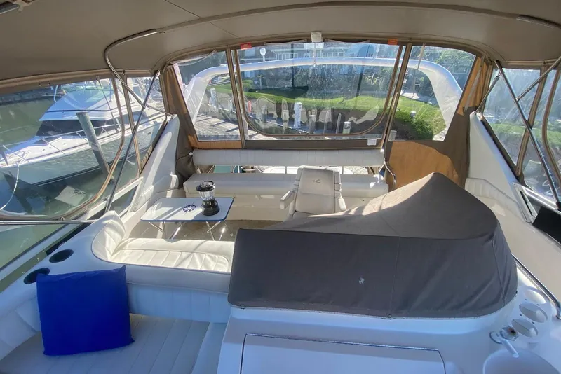 Slide: The Image of 1996 Sea Ray 440 Express Bridge interior with seating and table, docked at marina. - 11