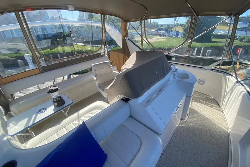 Slide: The Image of 1996 Sea Ray 440 Express Bridge interior with seating, table, and covered helm. - 12