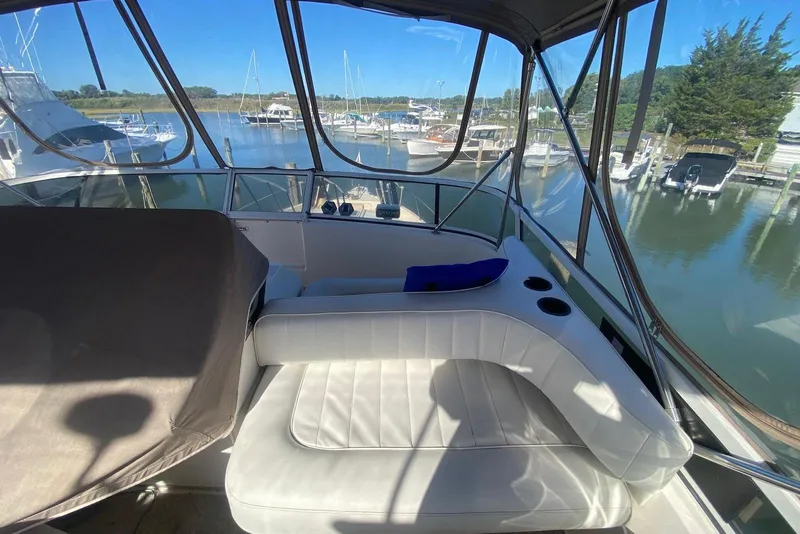 Slide: The Image of 1996 Sea Ray 440 Express Bridge interior with marina view, featuring white seating and cup holders. - 13
