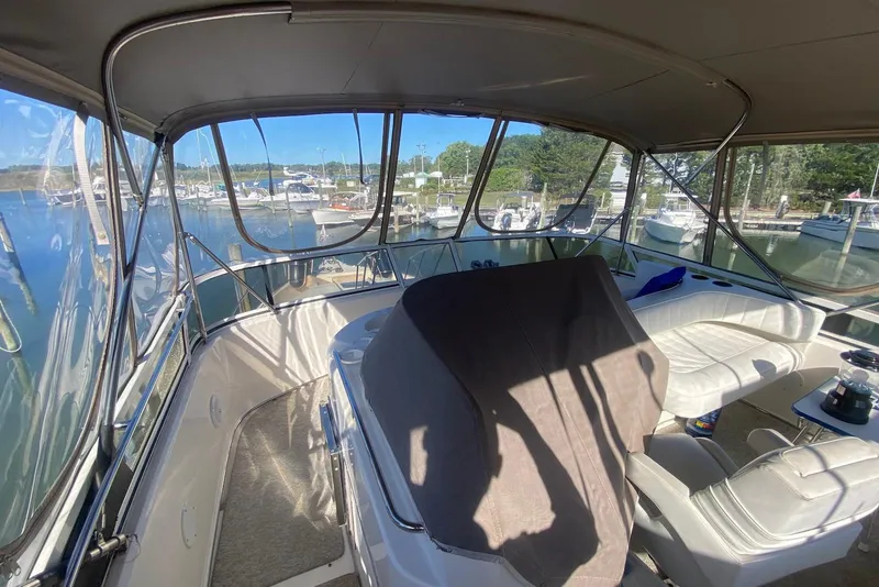 Slide: The Image of 1996 Sea Ray 440 Express Bridge interior with marina view, featuring seating and helm area. - 14