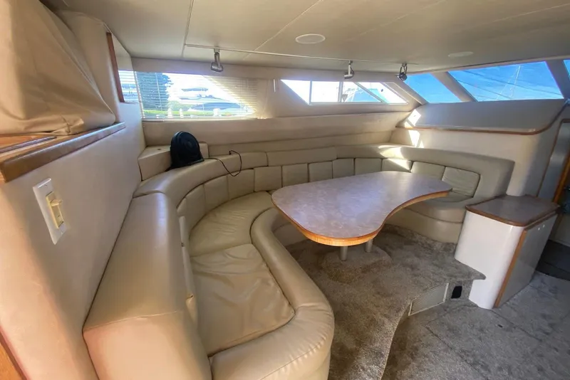 Slide: The Image of Interior of 1996 Sea Ray 440 Express Bridge with beige leather seating and wooden table. - 21
