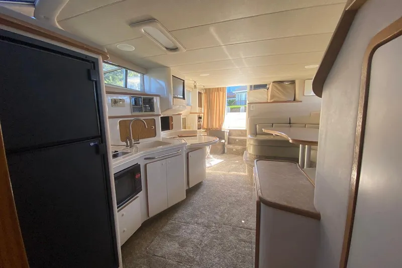 Slide: The Image of Interior of 1996 Sea Ray 440 Express Bridge yacht, featuring kitchen and seating area. - 23