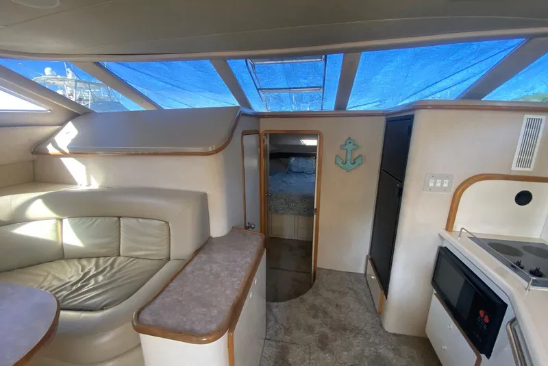 Slide: The Image of Interior of 1996 Sea Ray 440 Express Bridge yacht with seating, kitchenette, and skylight. - 27