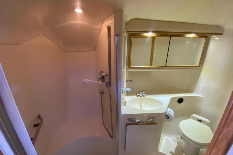 Slide: The Image of Bathroom interior of 1996 Sea Ray 440 Express Bridge yacht, featuring shower, sink, and toilet. - 28