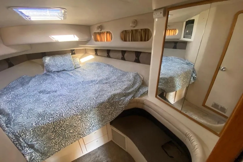 Slide: The Image of 1996 Sea Ray 440 Express Bridge cabin with bed, mirror, and natural light. - 30