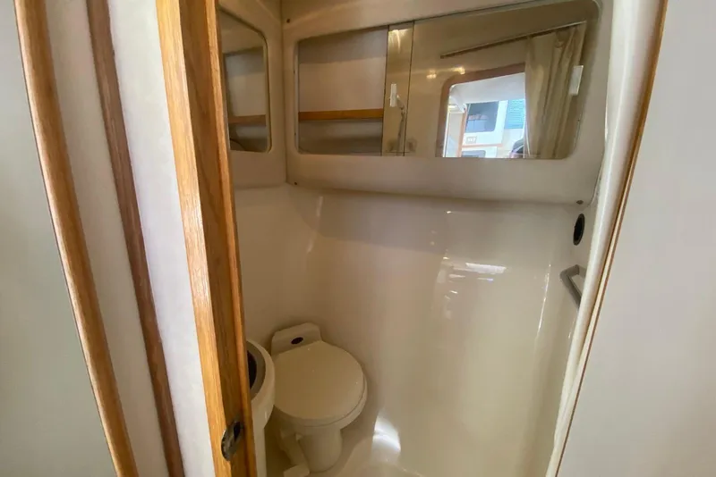 Slide: The Image of Bathroom interior of 1996 Sea Ray 440 Express Bridge yacht, featuring toilet and mirror. - 36