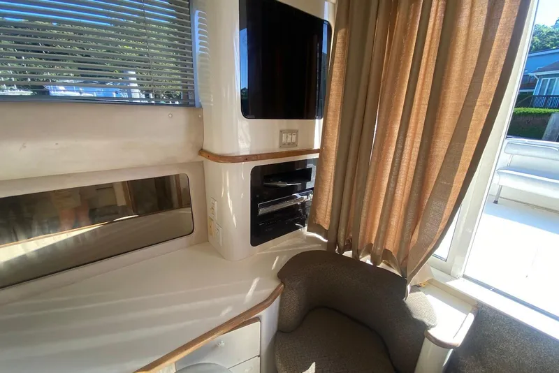 Slide: The Image of Interior of 1996 Sea Ray 440 Express Bridge with seating, window blinds, and entertainment system. - 44