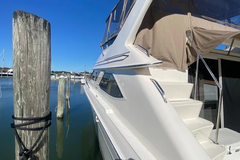 Slide: The Image of 1996 Sea Ray 440 Express Bridge yacht docked at marina, side view with stairs. - 7