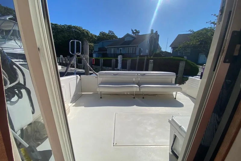 Slide: The Image of 1996 Sea Ray 440 Express Bridge boat deck with seating, docked near waterfront homes. - 8