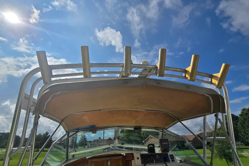 Slide: The Image of 1989 Hinterhoeller Limestone boat with rod holders under a sunny blue sky. - 11