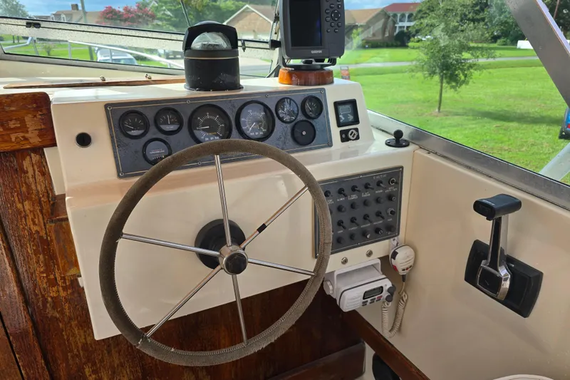 Slide: The Image of 1989 Hinterhoeller Limestone boat dashboard with steering wheel, gauges, and control panel. - 13