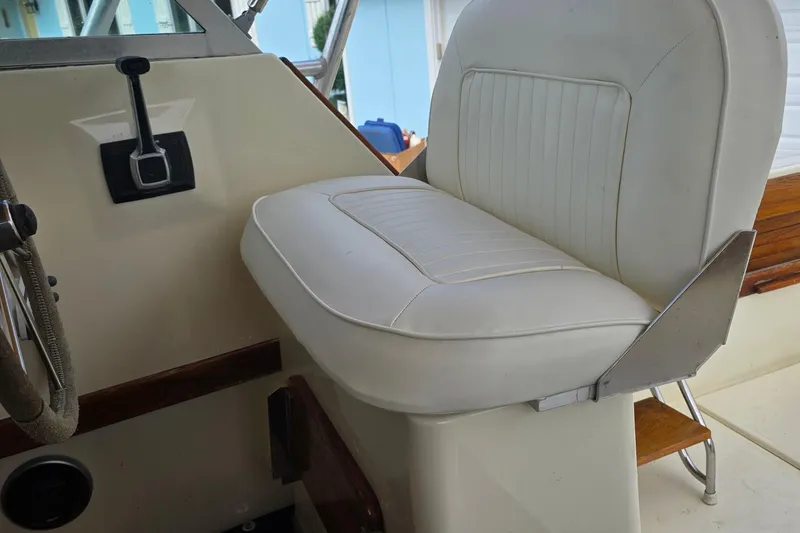Slide: The Image of 1989 Hinterhoeller Limestone boat interior with white cushioned seat and control lever. - 23