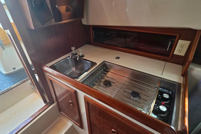 Slide: The Image of 1989 Hinterhoeller Limestone boat interior with compact kitchen, featuring sink and stove. - 32