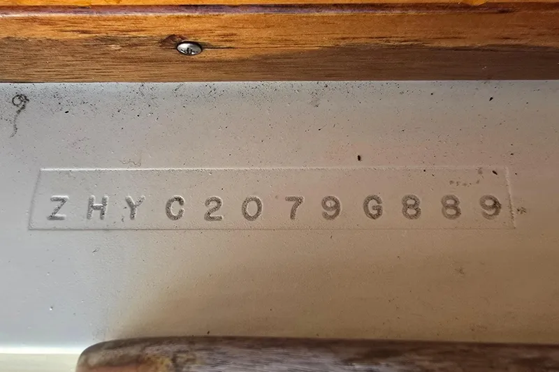 Slide: The Image of 1989 Hinterhoeller Limestone boat hull identification number, ZHYC2079G889, on a wooden surface. - 35