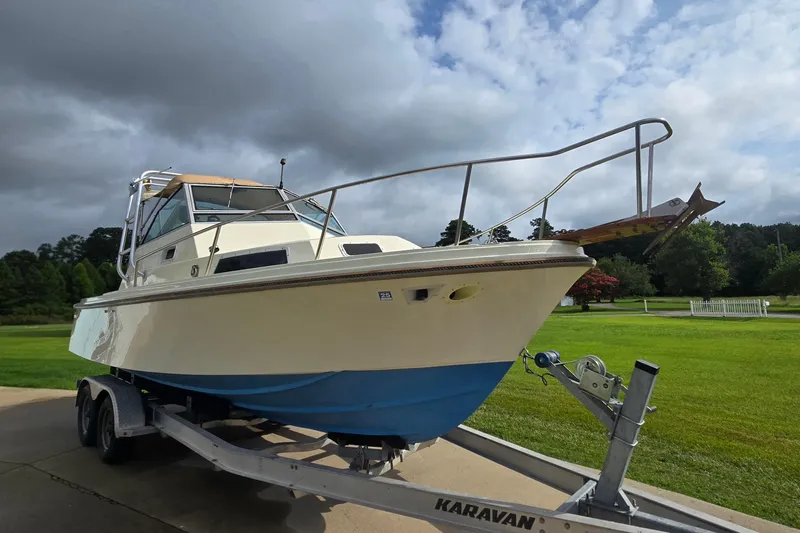 Slide: The Image of 1989 Hinterhoeller Limestone boat on Karavan trailer, parked on a driveway with lush greenery. - 36
