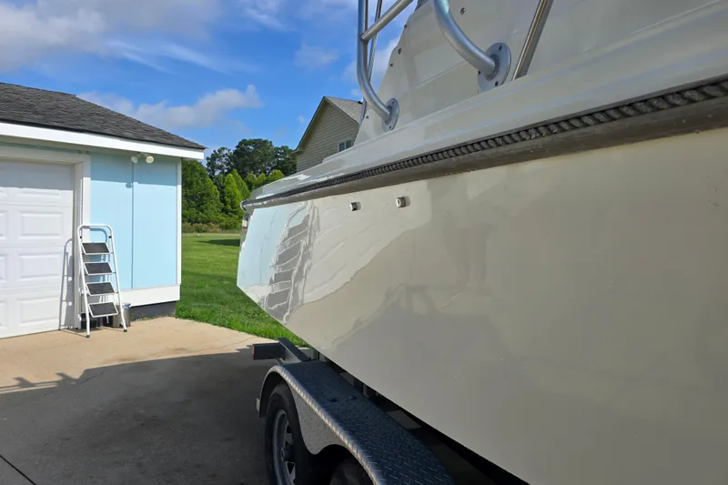 Slide: The Image of 1989 Hinterhoeller Limestone boat on trailer beside a garage, under a clear blue sky. - 38