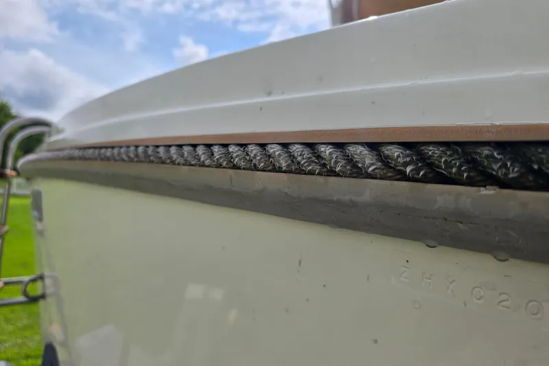 Slide: The Image of 1989 Hinterhoeller Limestone boat detail with textured rope and hull, under a cloudy sky. - 7