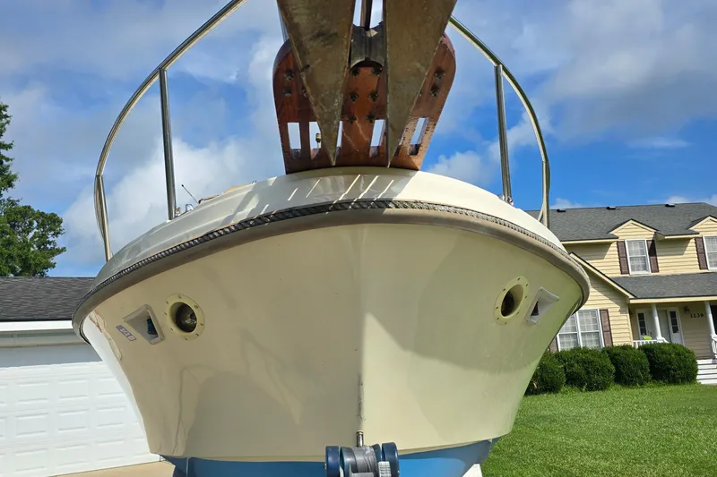 Slide: The Image of 1989 Hinterhoeller Limestone boat in driveway, under a clear blue sky. - 8
