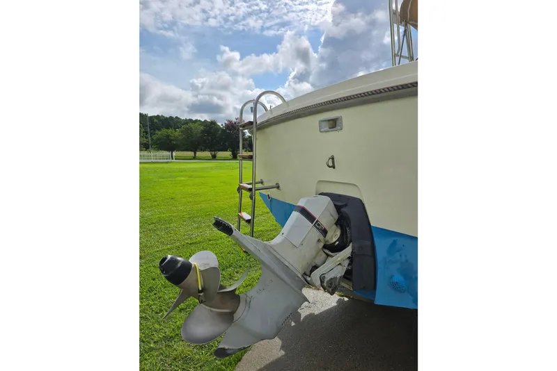Slide: The Image of 1989 Hinterhoeller Limestone boat with outboard motor, parked on grassy field under cloudy sky. - 9