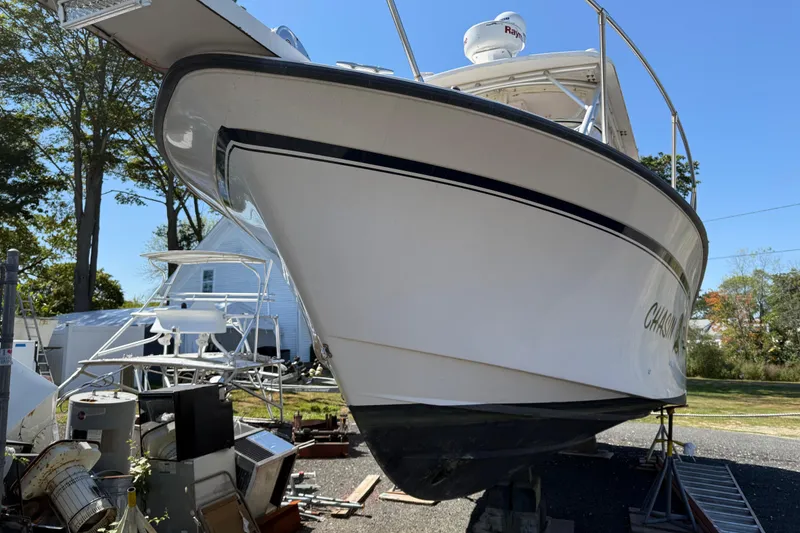 Slide: The Image of 1996 Grady-White Marlin 300 boat on land, surrounded by equipment and trees. - 3