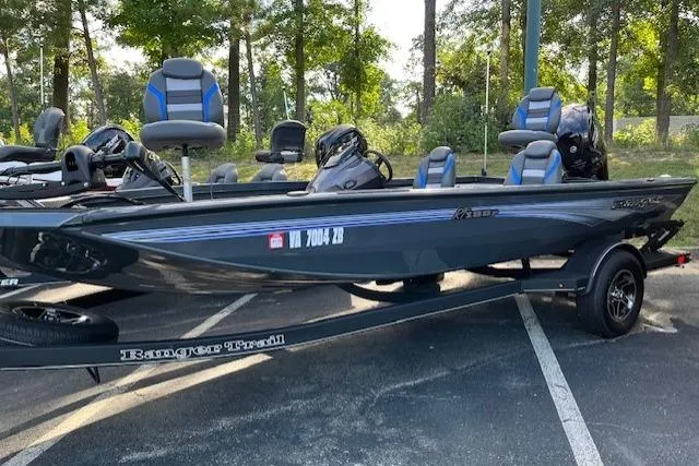 The Image of 2025 Ranger RT188P boat on trailer in wooded parking area. - 0