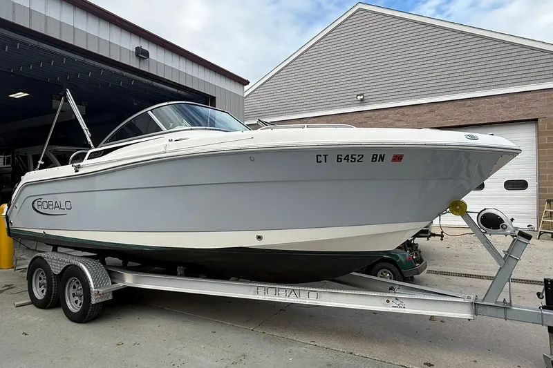 Slide: The Image of 2021 Robalo R227 Dual Console boat on trailer outside a garage. - 2