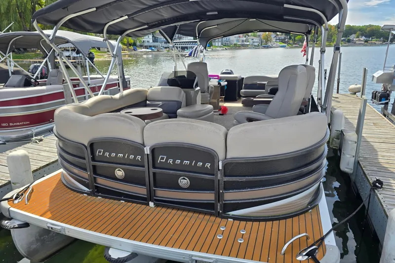 Slide: The Image of 2013 Premier 275 Boundary Waters pontoon boat docked on a serene lake. - 2