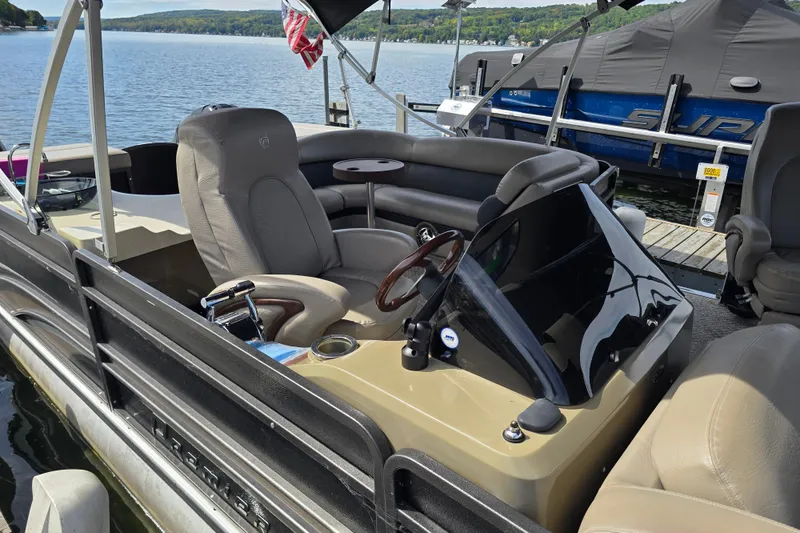 Slide: The Image of 2013 Premier 275 Boundary Waters pontoon boat interior at dock, featuring steering console and seating. - 8